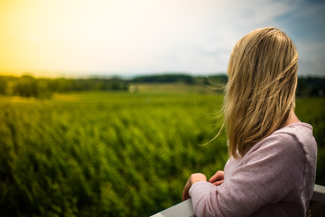 girl in pink hoodie standing on green grass field during daytime