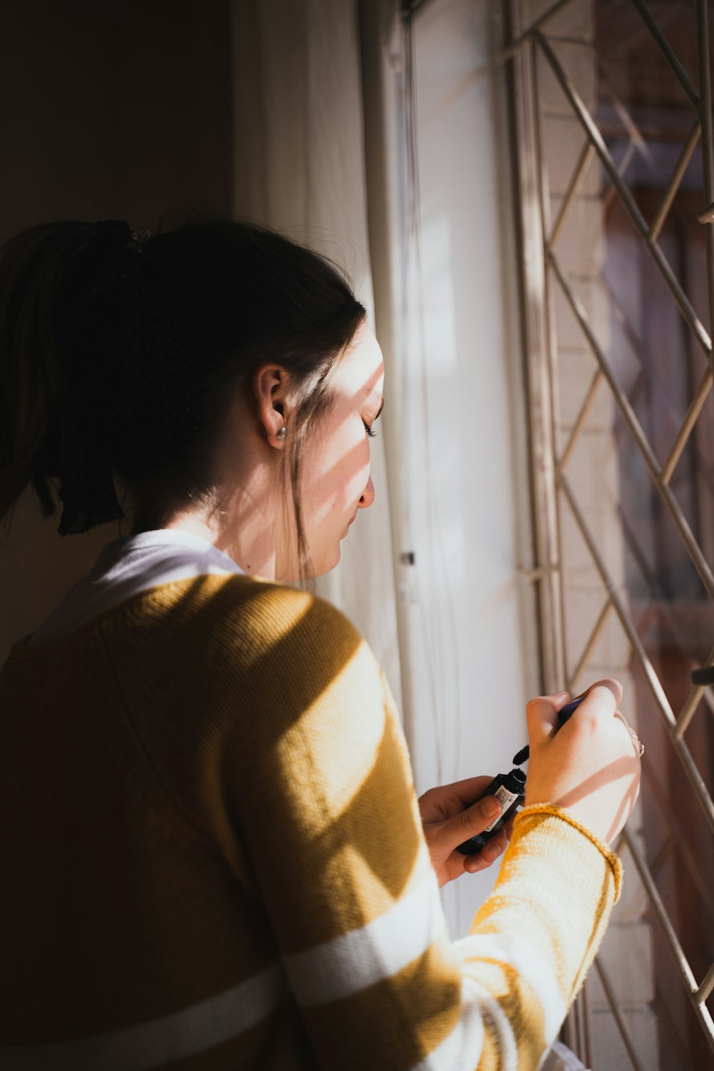 woman in brown sweater holding smartphone