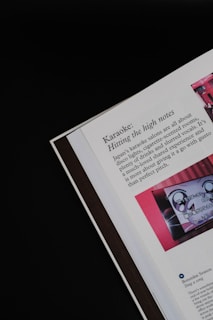 An open page of a book or magazine lies partially viewable against a black background. The prominent topic is 'Karaoke: Hitting the high notes,' which describes Japan's karaoke salons. There is an image with red tones next to the text, depicting what seems to be a karaoke machine or screen.