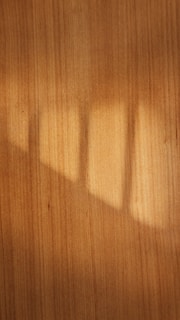 A warm brown wooden texture with sunlight casting soft shadows.