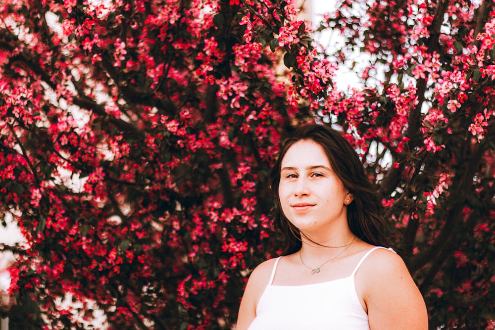 woman in white tank top standing under red leaf tree