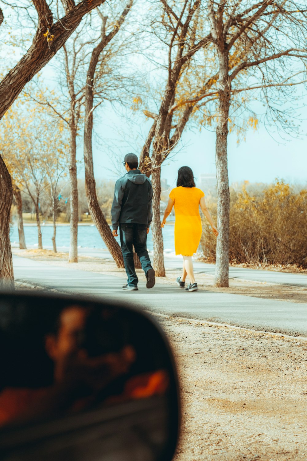 man in black jacket and gray pants standing beside woman in yellow dress