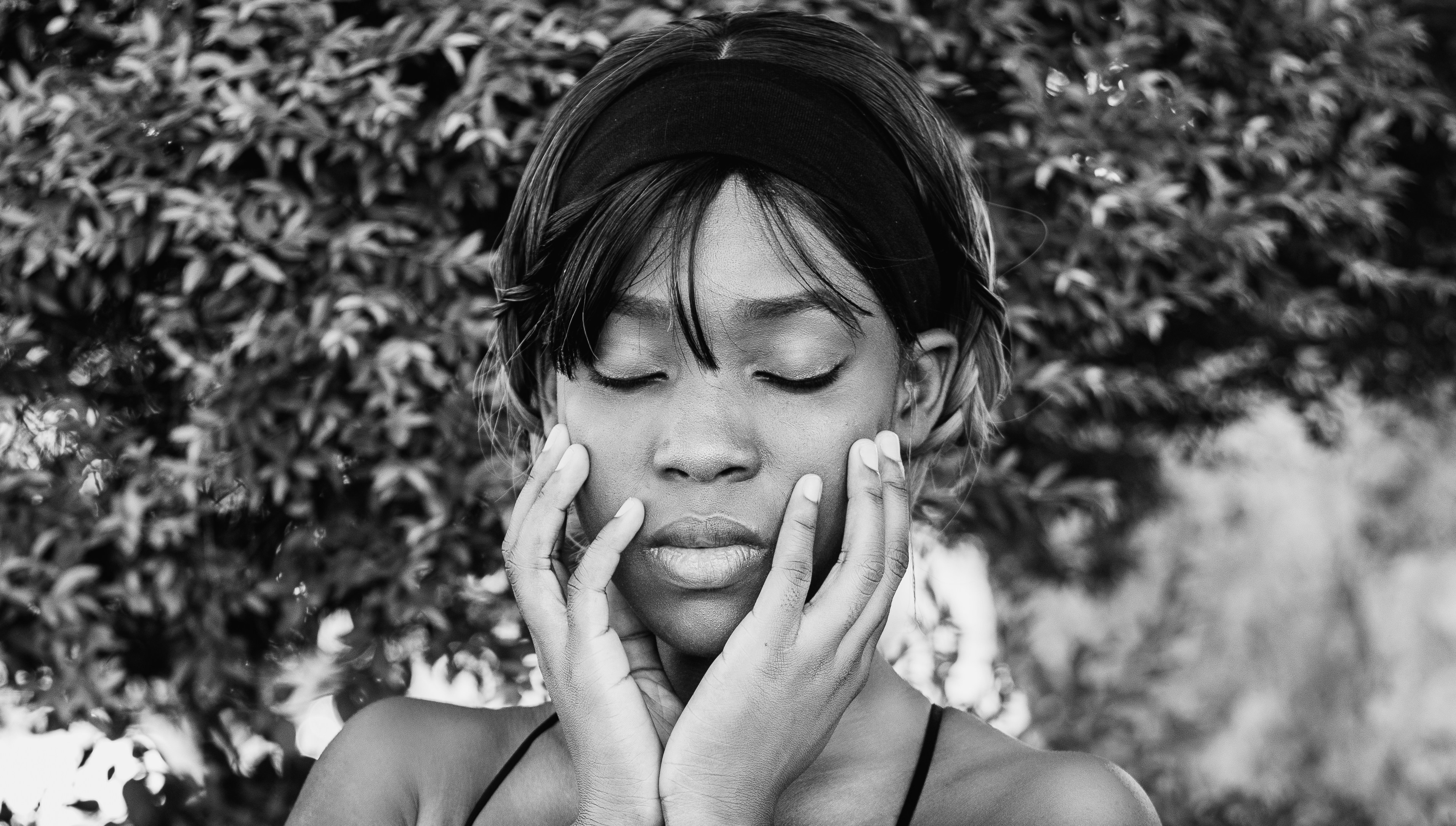 grayscale photo of woman covering her face with her hand