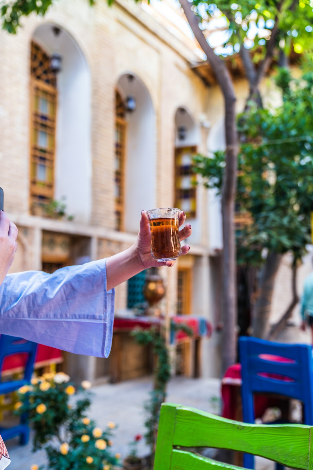 person holding clear drinking glass with brown liquid