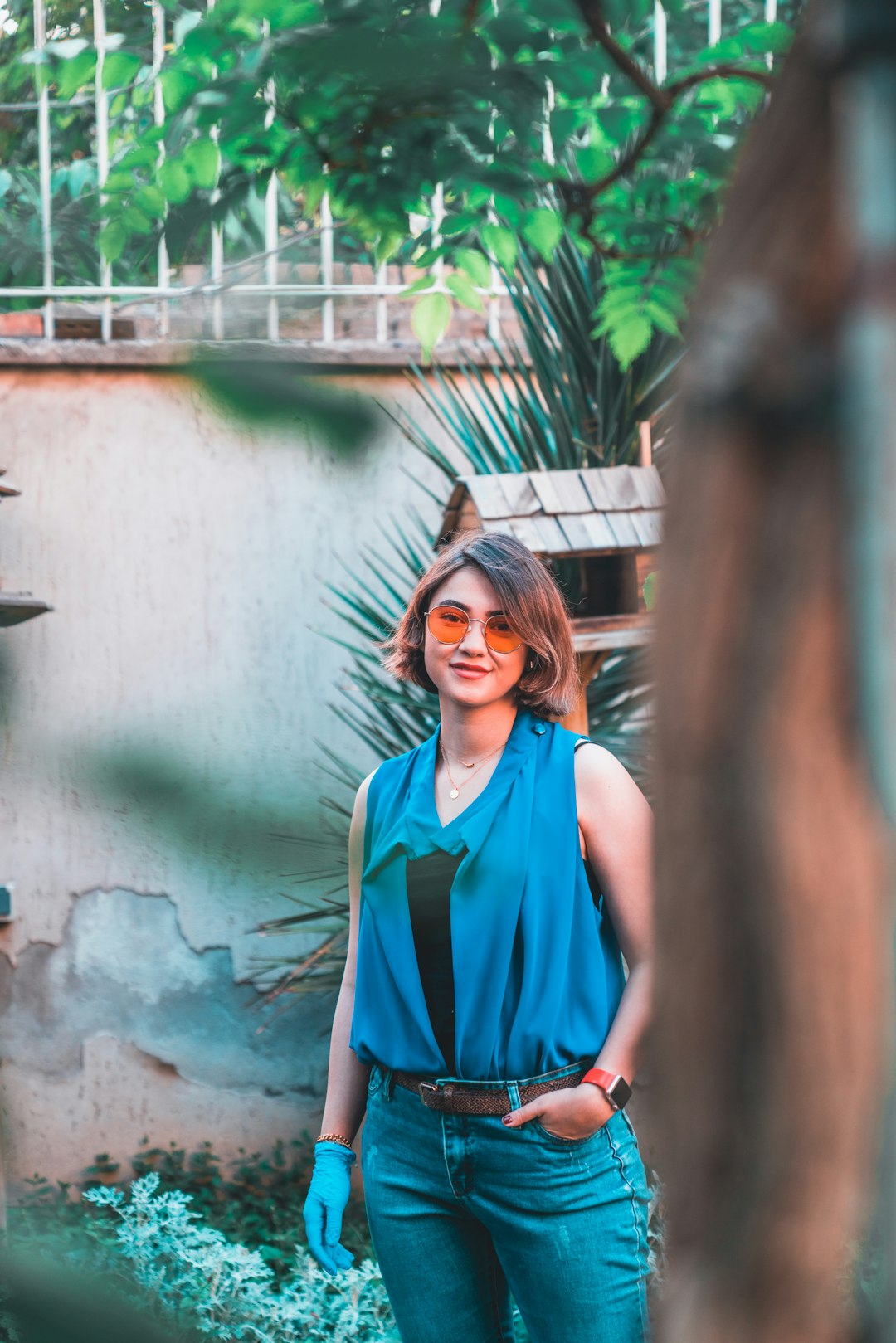 woman in blue sleeveless dress standing beside brown wooden wall during daytime