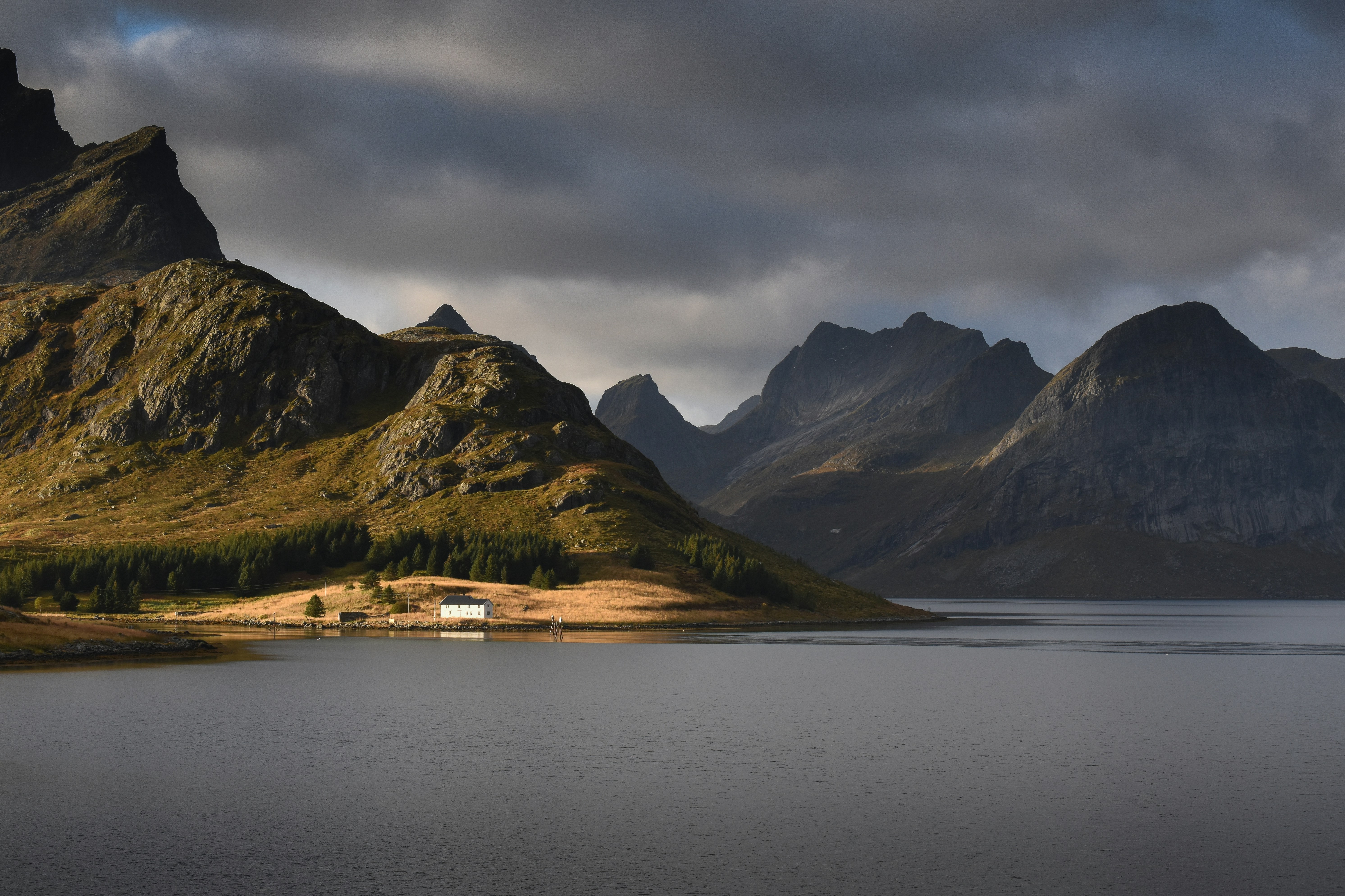 lake near mountain under cloudy sky during daytime