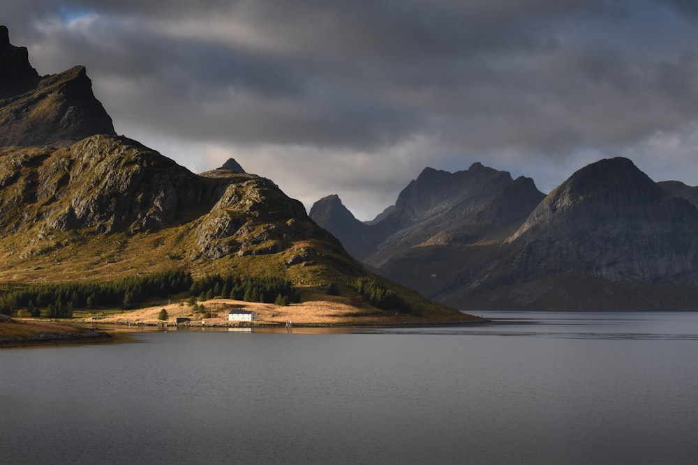 lake near mountain under cloudy sky during daytime