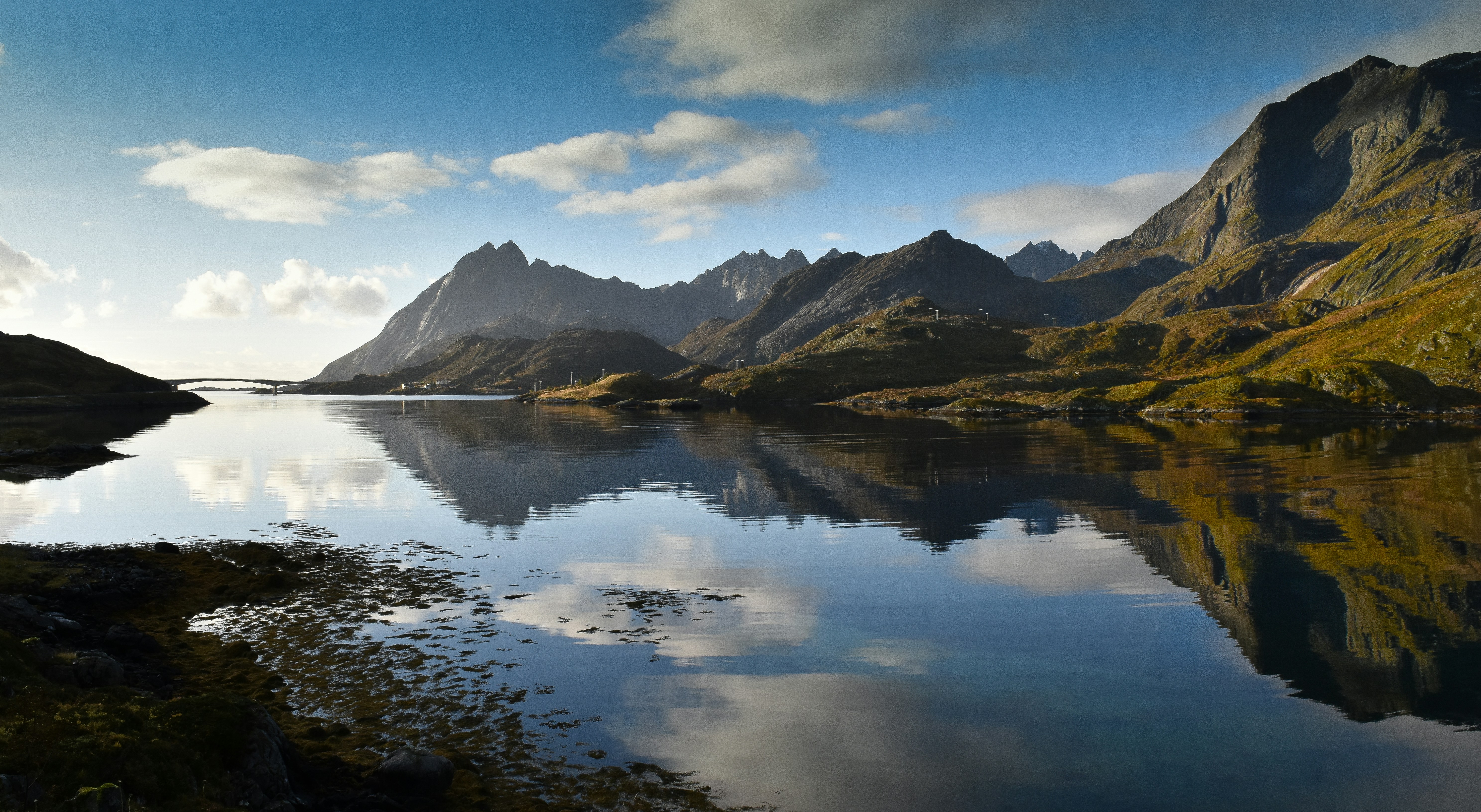 brown mountains near body of water under blue sky during daytime