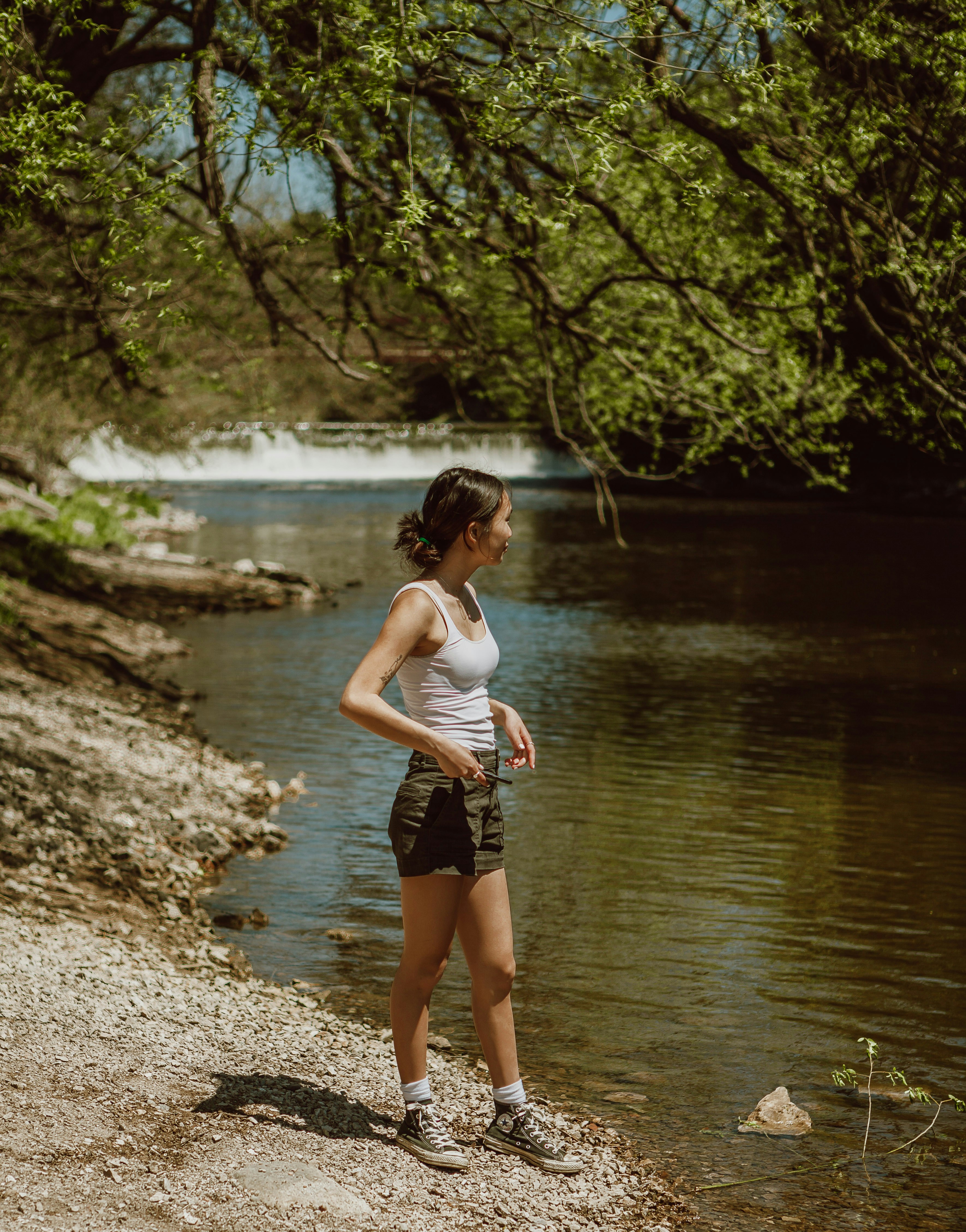 woman in white tank top and black shorts standing on river during daytime