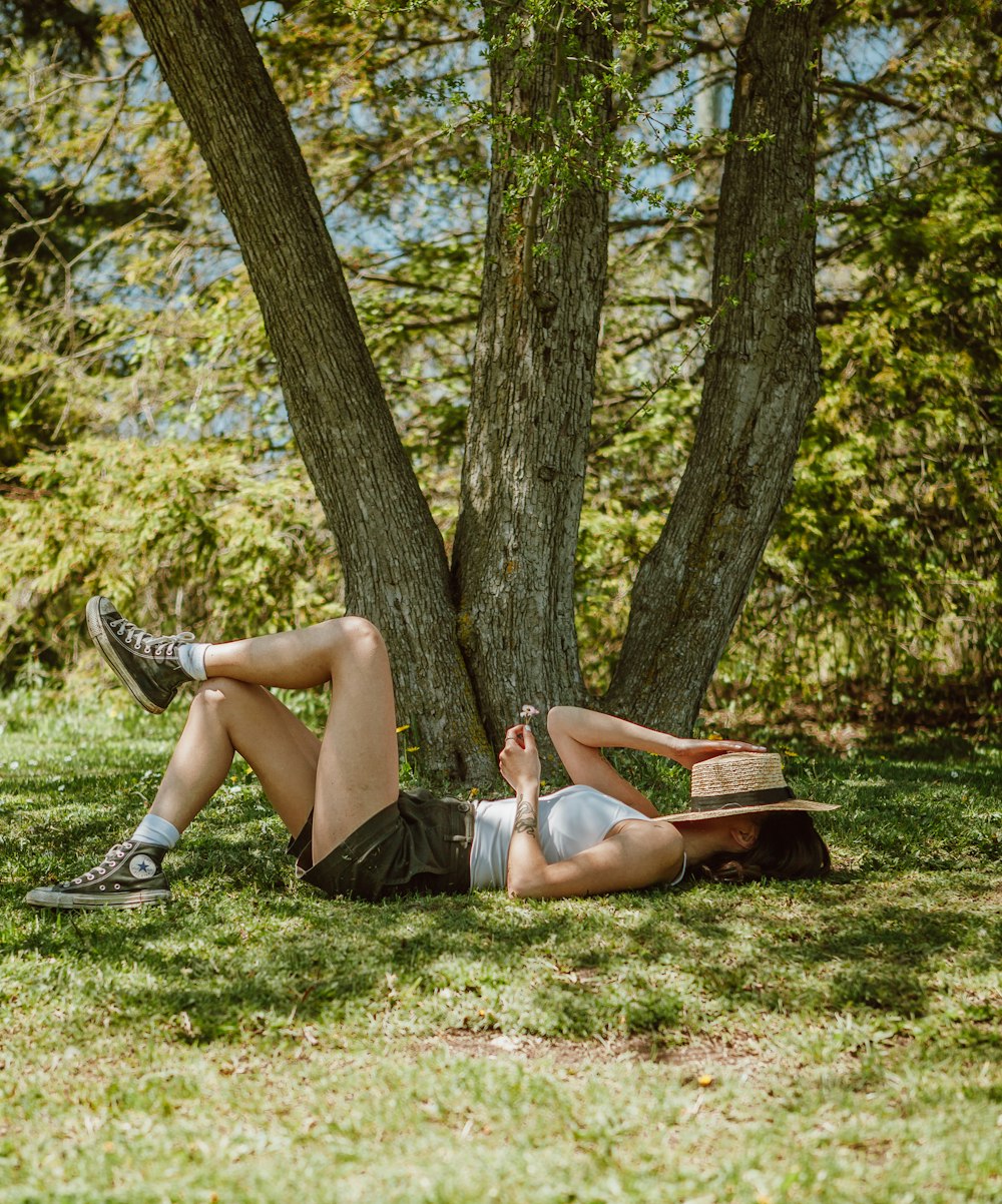 woman in black shorts lying on green grass field during daytime