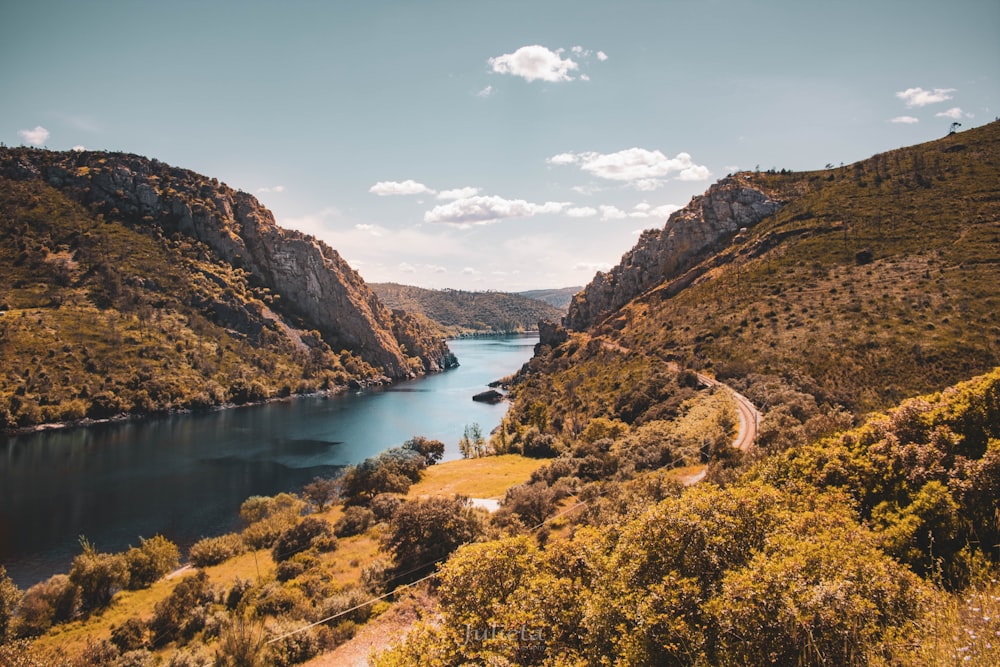 brown and green mountains beside river under blue sky during daytime