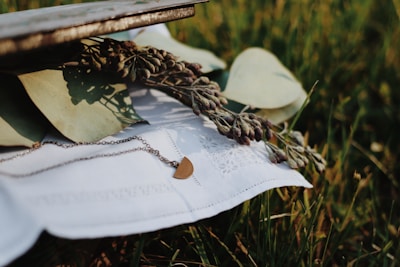 Close-up of a delicate, handmade necklace resting on a bed of wildflowers under soft natural light.