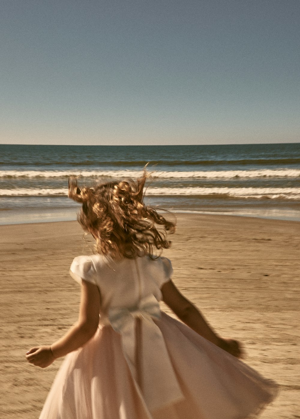 woman in white dress sitting on beach during daytime