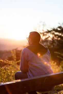 man sitting on a bench looking at sunset