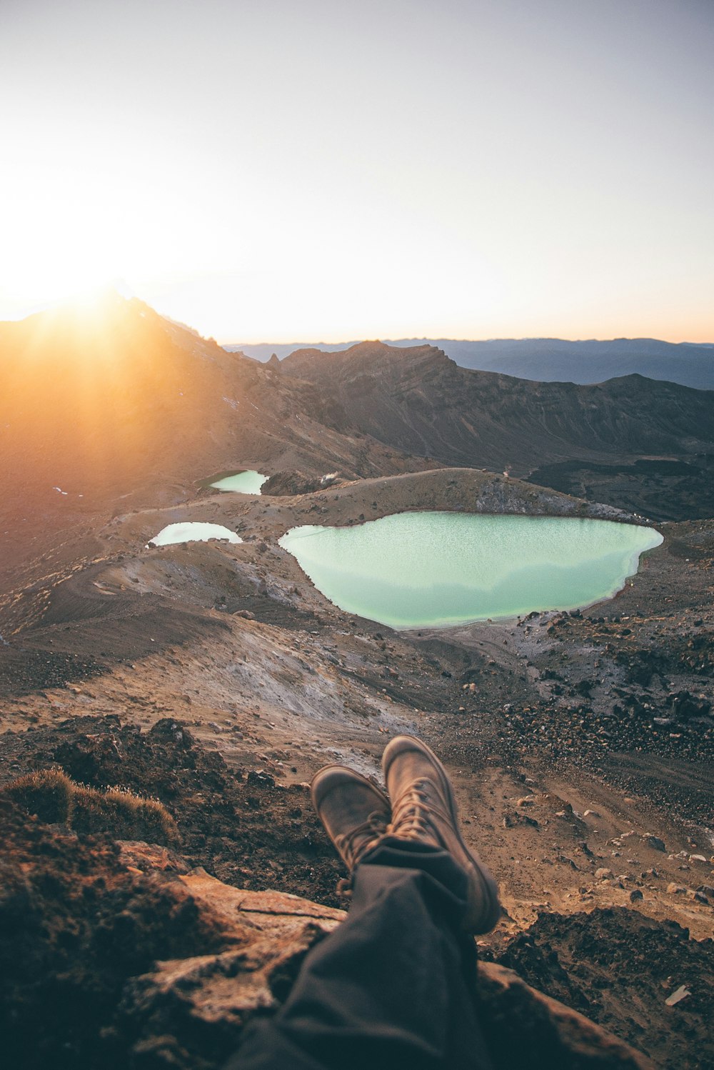 person in brown hiking shoes sitting on rock formation during daytime