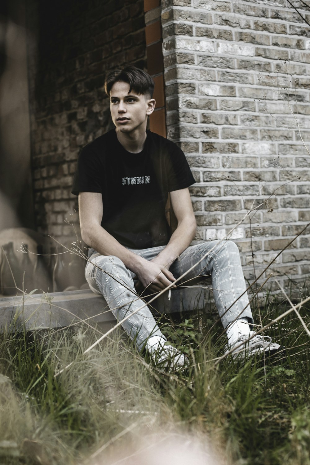 man in black crew neck t-shirt and blue denim jeans sitting on green grass during