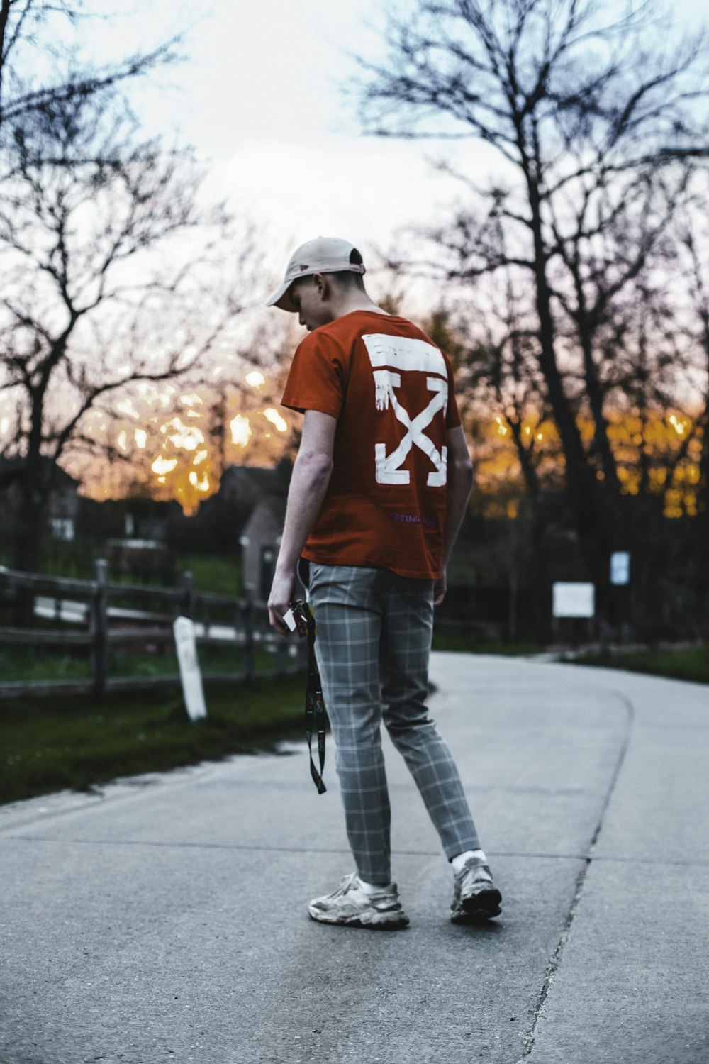 hombre con camiseta roja y blanca de cuello redondo y jeans de mezclilla azules sosteniendo negro y