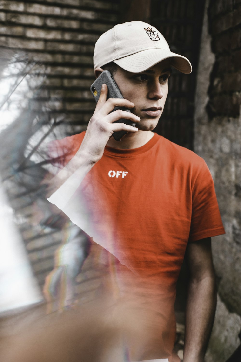 homem em t-shirt vermelha pescoço da tripulação segurando smartphone preto