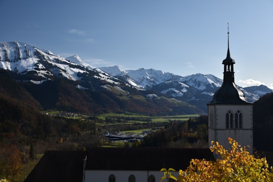 white and black concrete building near green trees and snow covered mountains during daytime in Chapel and Cemetary Switzerland