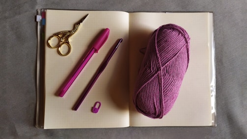 A cozy workspace with yarn, crochet hooks, and a handwritten note inviting contact.