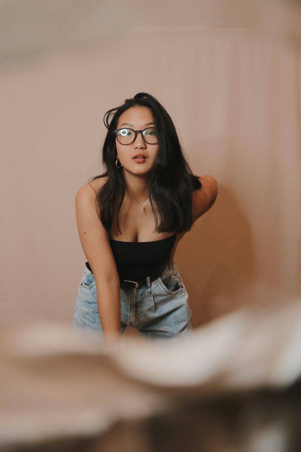 woman in black tank top and blue denim shorts wearing black framed eyeglasses