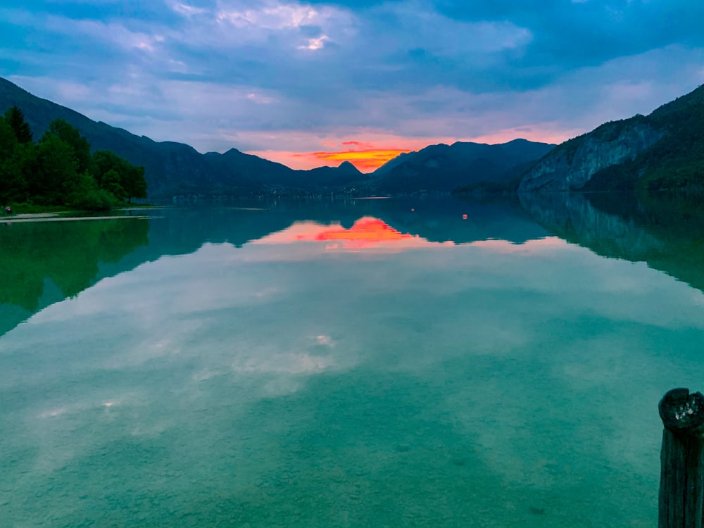 lake near mountain under cloudy sky during daytime