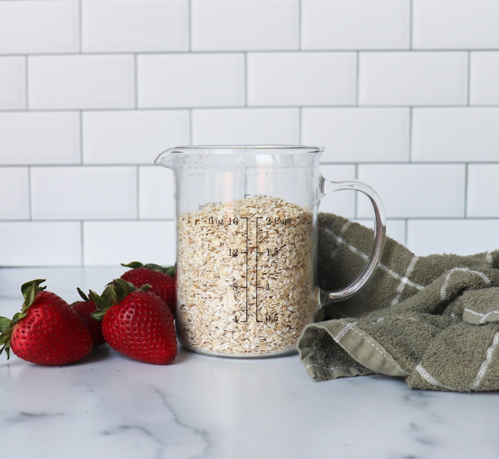 strawberries on white ceramic bowl beside clear glass pitcher