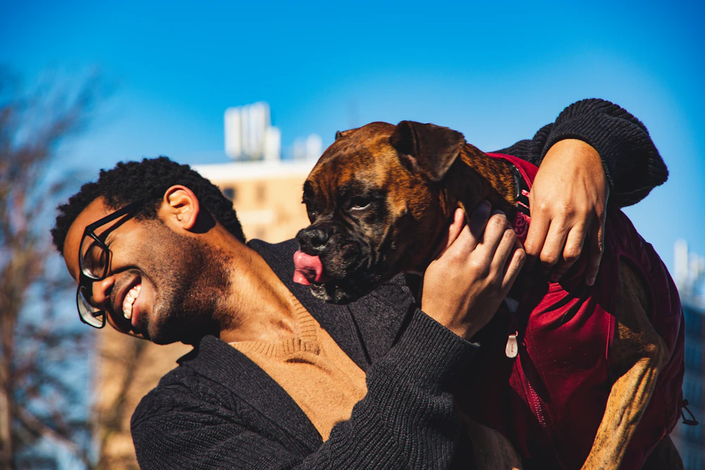 Resident in a black sweater hugging his short-coated dog