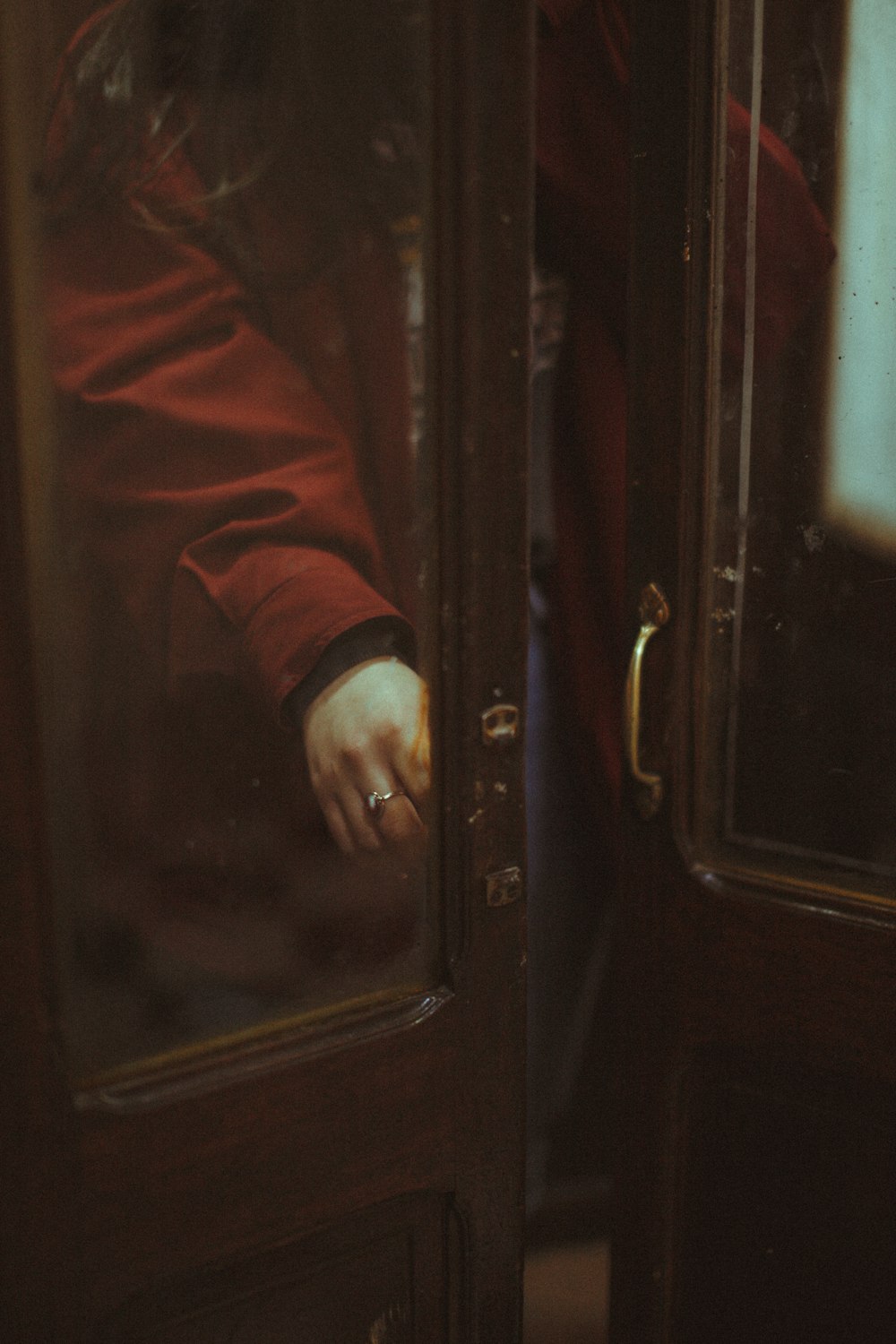 person in red coat standing in front of black wooden door