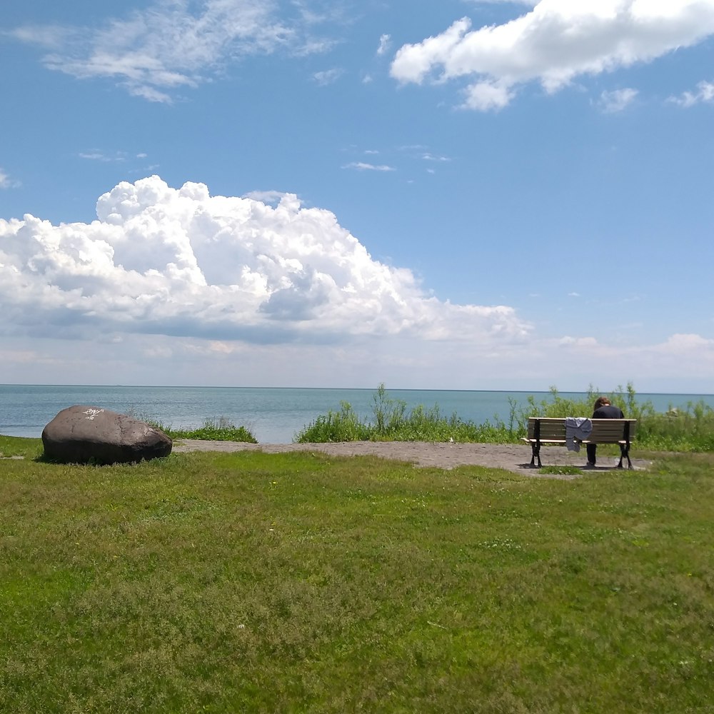 a man sitting on a bench next to a body of water