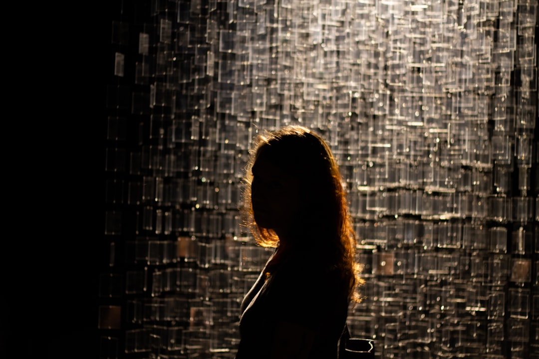 woman in black tank top standing beside gray brick wall