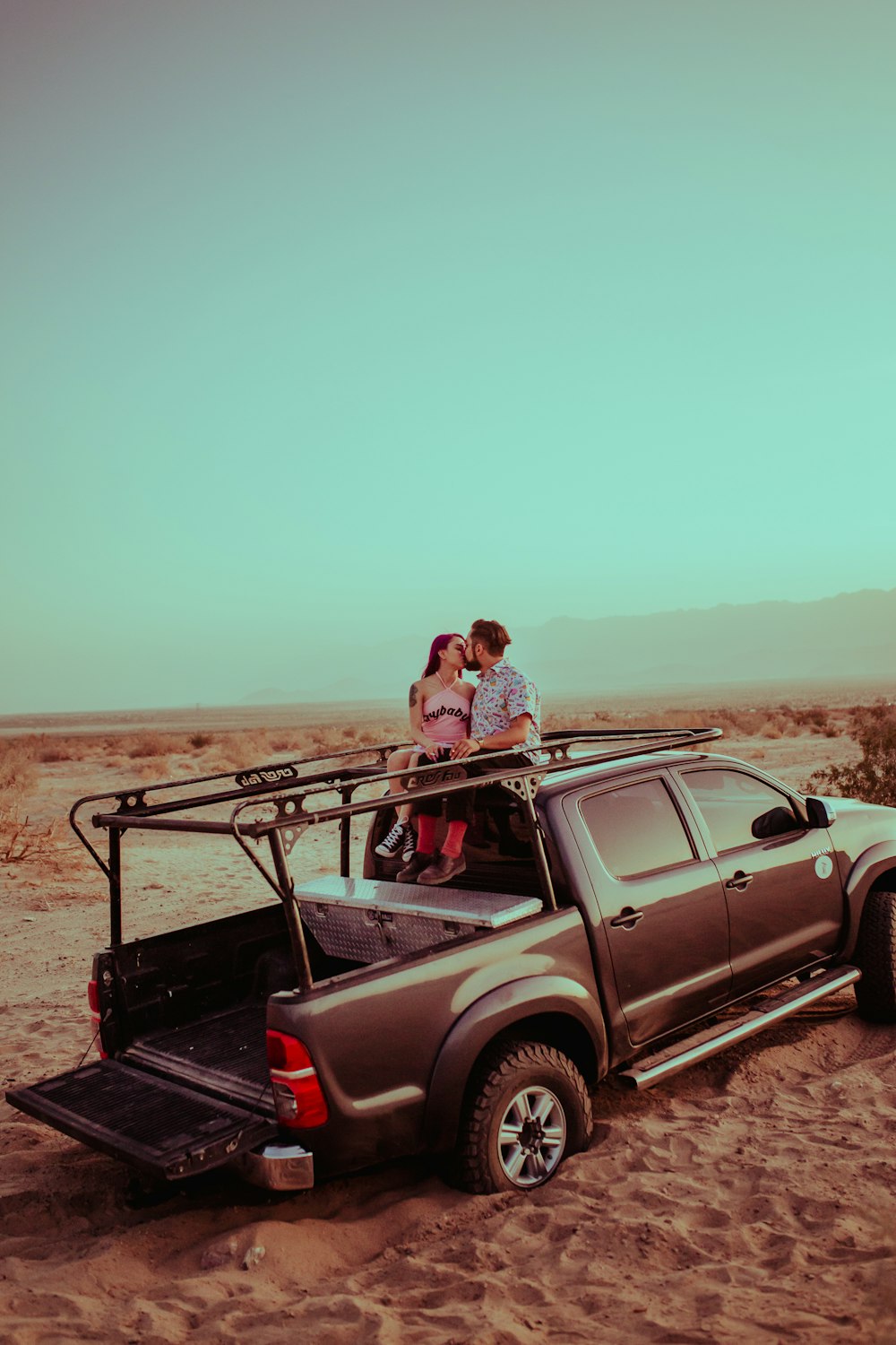 Mann und Frau sitzen tagsüber auf schwarzem SUV