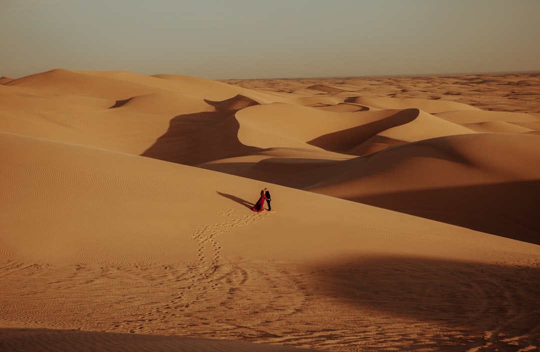 person in red shirt standing on desert during daytime
