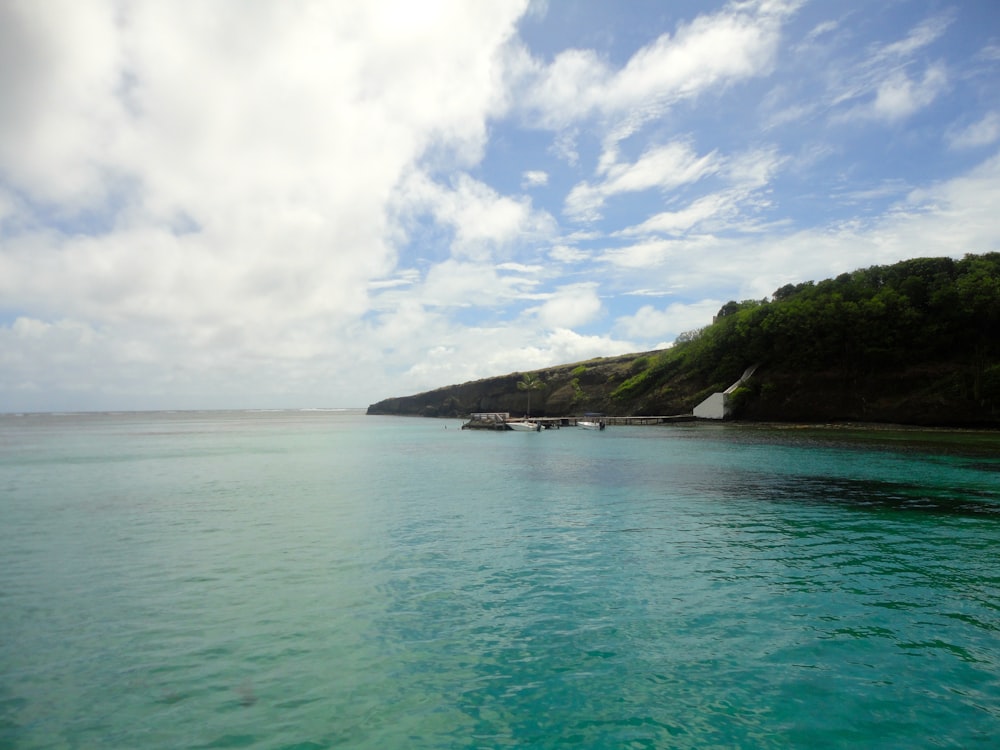 Isla verde en el mar azul bajo el cielo azul y las nubes blancas durante el día