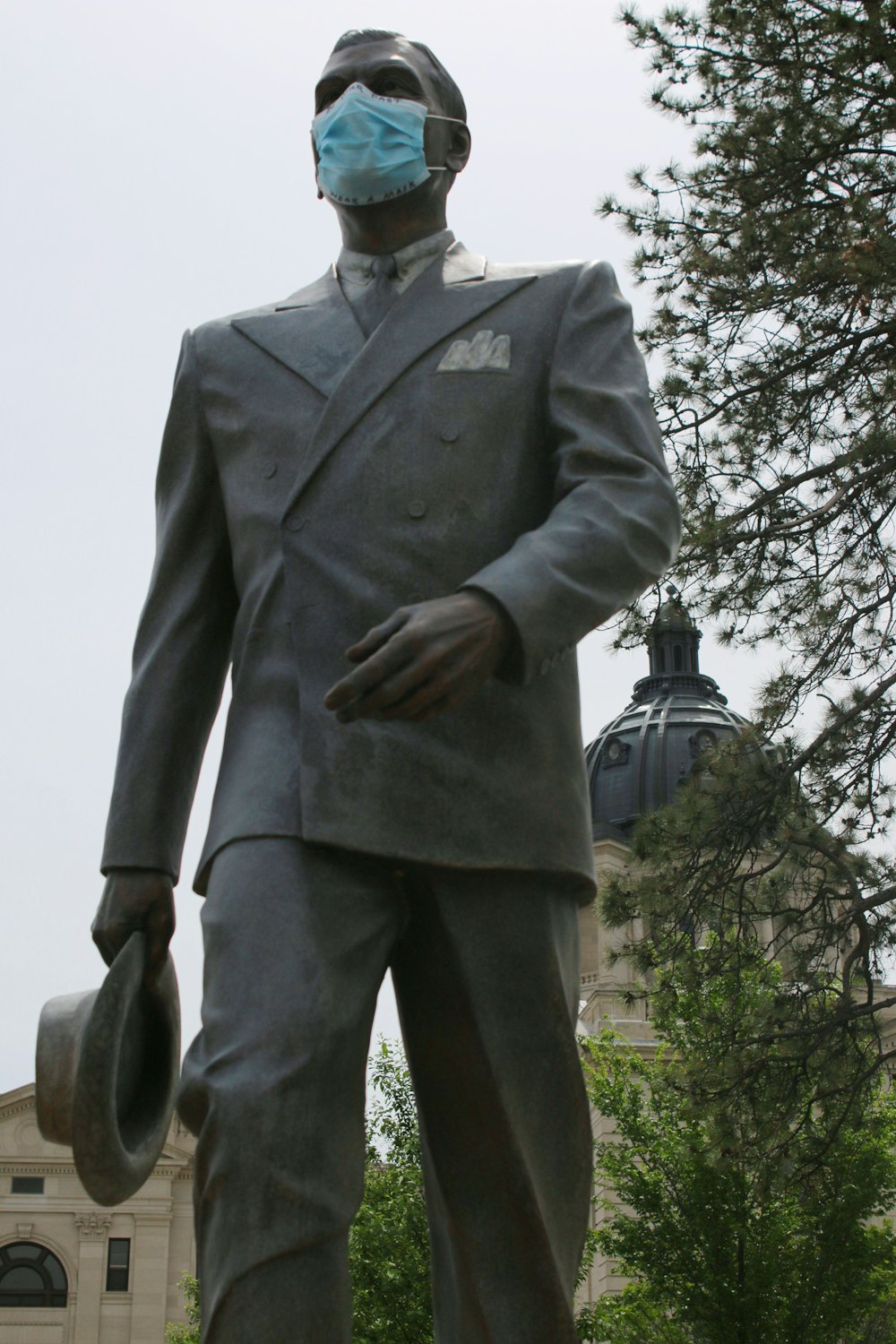 man in gray suit standing near bare tree during daytime