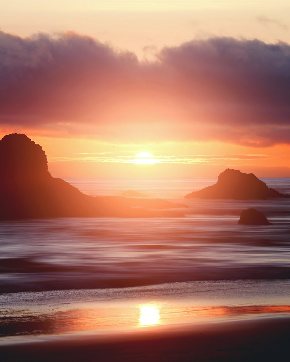 silhouette of mountain near body of water during sunset