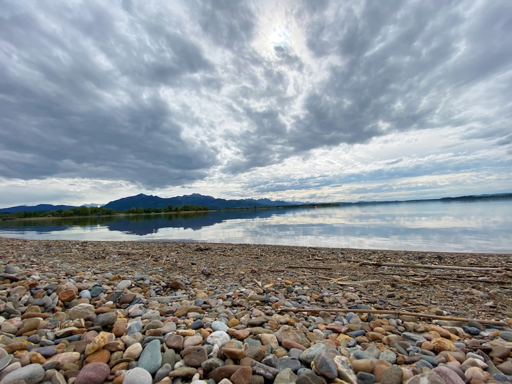 a rocky beach with a body of water in the background