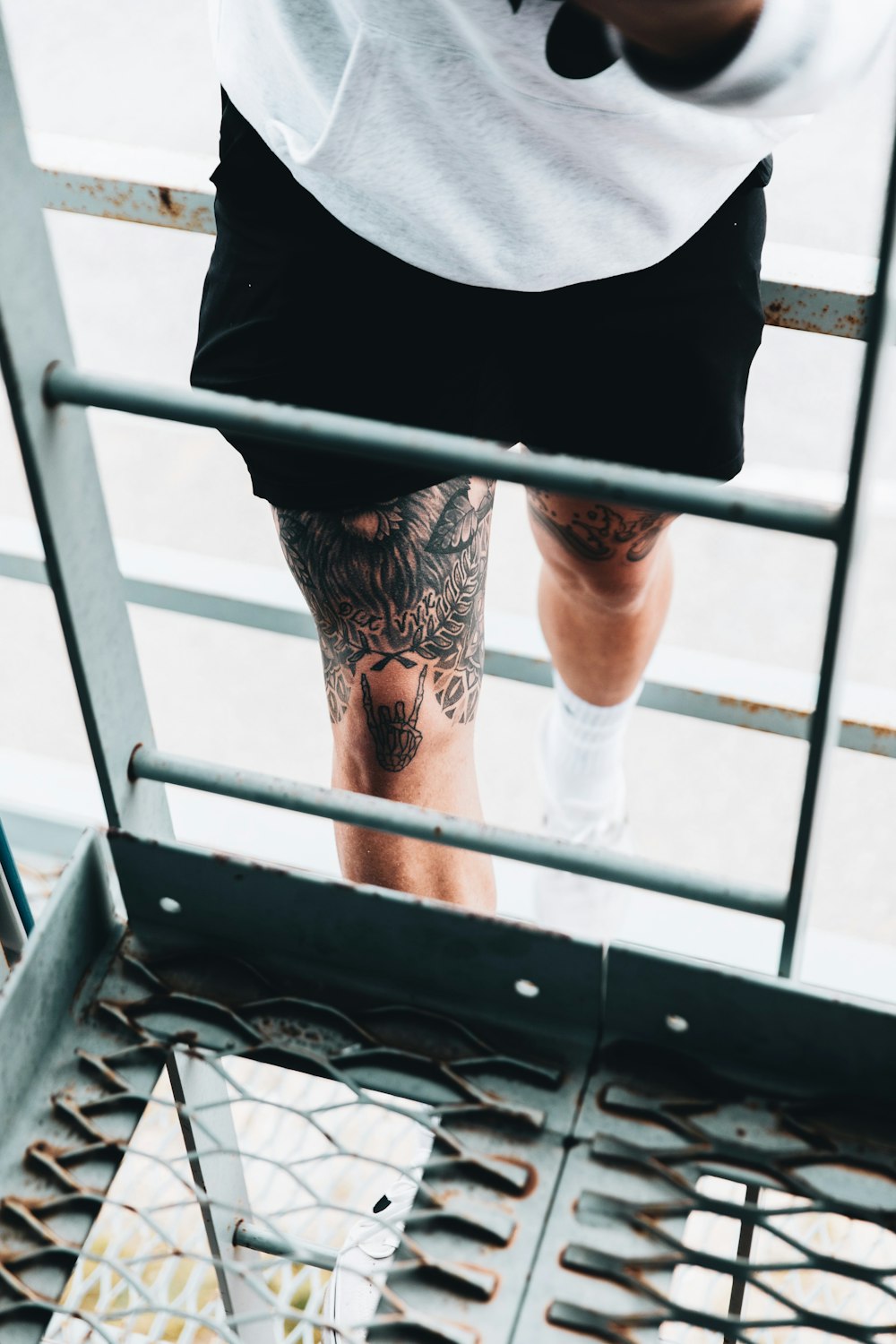 person in black shirt and black and white floral skirt standing on black metal railings