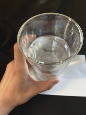 Hands holding the Omega Final product next to a glass of water