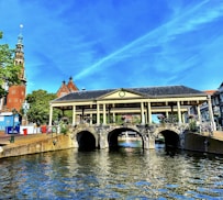 brown and white concrete building beside river under blue sky during daytime