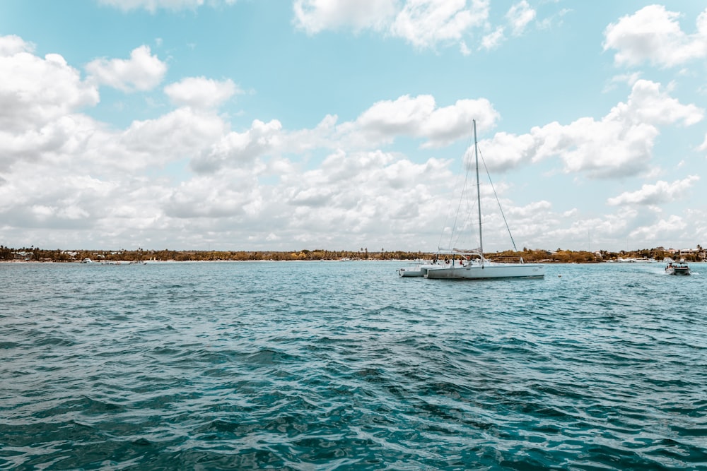 white boat on sea under blue sky and white clouds during daytime