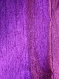 A rich purple fabric with a textured surface, exhibiting different shades and subtle variations in color.