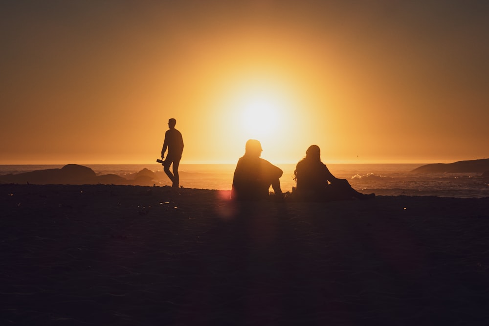 a group of people sitting on top of a sandy beach