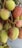 Clusters of lychee fruit hanging from branches, displaying a textured skin with a mix of red and green colors.
