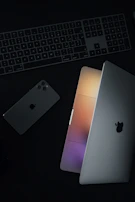A minimalist workstation with a laptop, smartphone, and notebook under soft lighting
