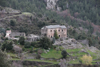 Spacious rustic stone house surrounded by lush greenery on a rocky outcrop.