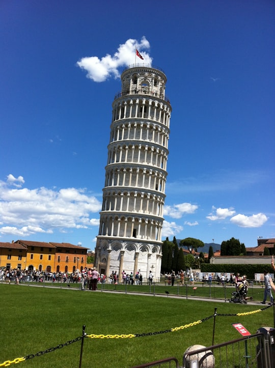 people walking on green grass field near white concrete building during daytime in Piazza dei Miracoli Italy