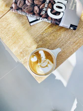 Close-up of a latte art cup next to an open ebook about interview skills.
