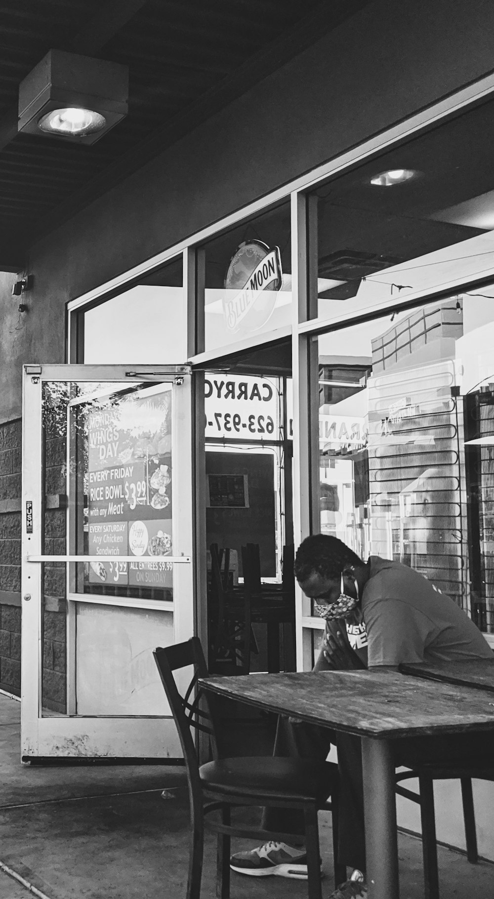 homme en veste noire assis sur une chaise devant le magasin