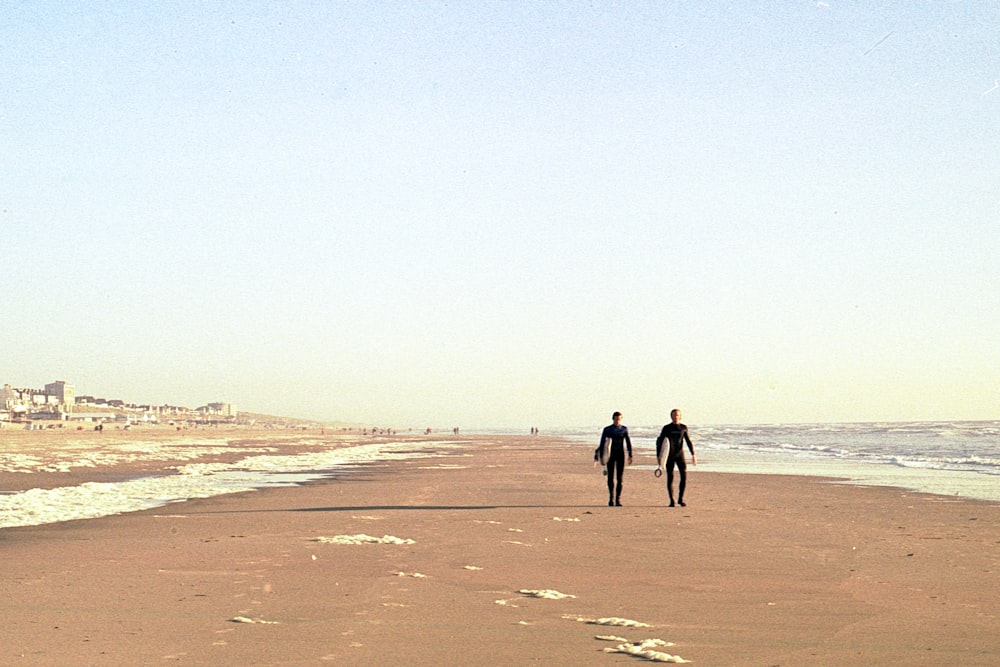 2 person walking on brown sand during daytime